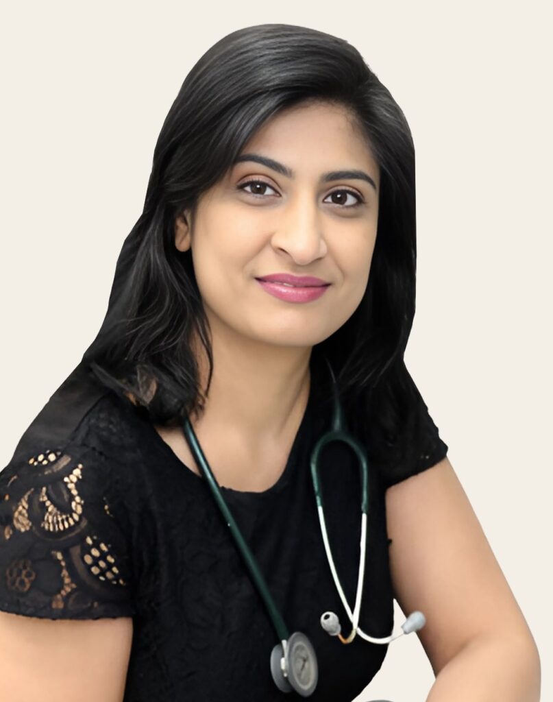 A woman with medium-length dark hair wearing a black lace top and a stethoscope around her neck, smiling at the camera with a neutral background.